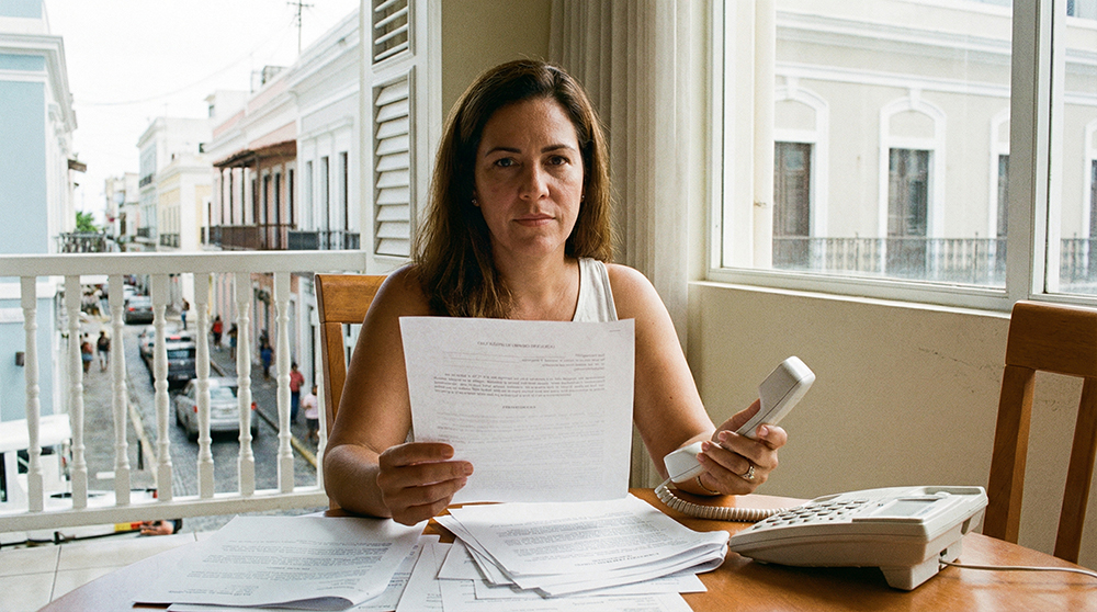 Mujer preocupada sostiene el teléfono en una mano y notificación de deuda en la otra.