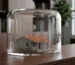 Una maqueta arquitectónica detallada y bellamente elaborada de una clásica casa puertorriqueña de hormigón, colocada de forma segura dentro de una pesada campana de cristal transparente.